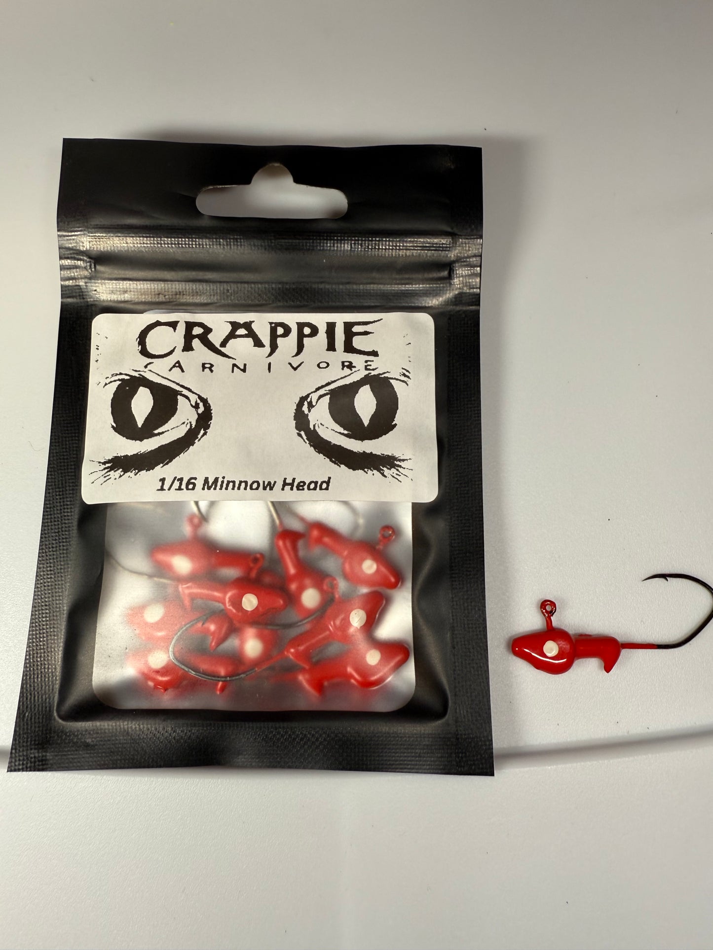 Red minnow jig heads in a pack, featuring sickle style hooks, 1/16oz size, ideal for fishing enthusiasts.
