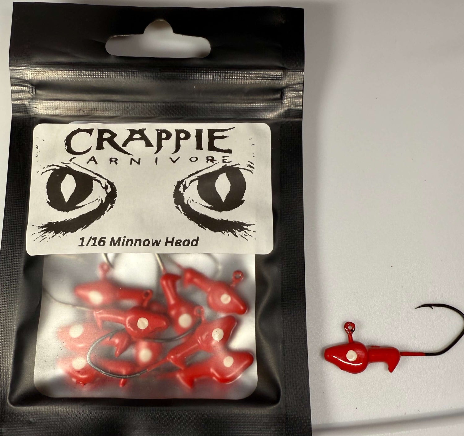 Red minnow jig heads in a pack, featuring sickle style hooks, 1/16oz size, ideal for fishing enthusiasts.